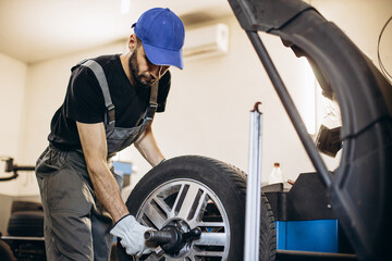 Fototapeta na wymiar Repairman at car service changing tires