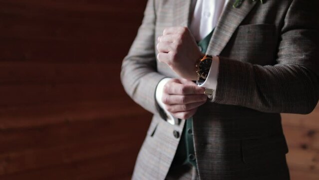 The man adjusts his cufflinks on the sleeves. Groom preparing for a wedding day.