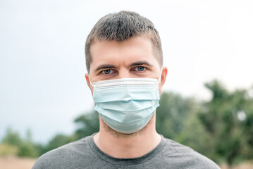 Portrait of handsome man in medical blue mask with green eyes due to outbreak of pandemic...