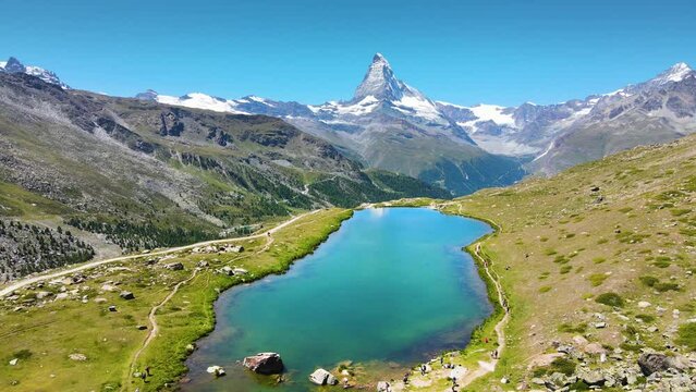 View of Matterhorn peak from Zermatt, Switzerland on the five lakes hike. Scenic summer alpine panorama with blue sky and white summits in Swiss Alps. Aerial video footage.