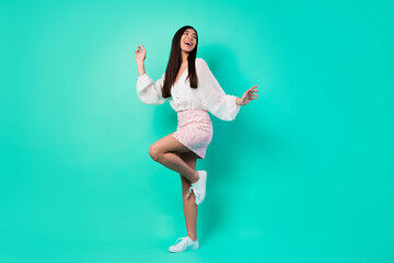 Full length portrait of positive carefree malaysian girl enjoy dancing partying isolated on emerald color background