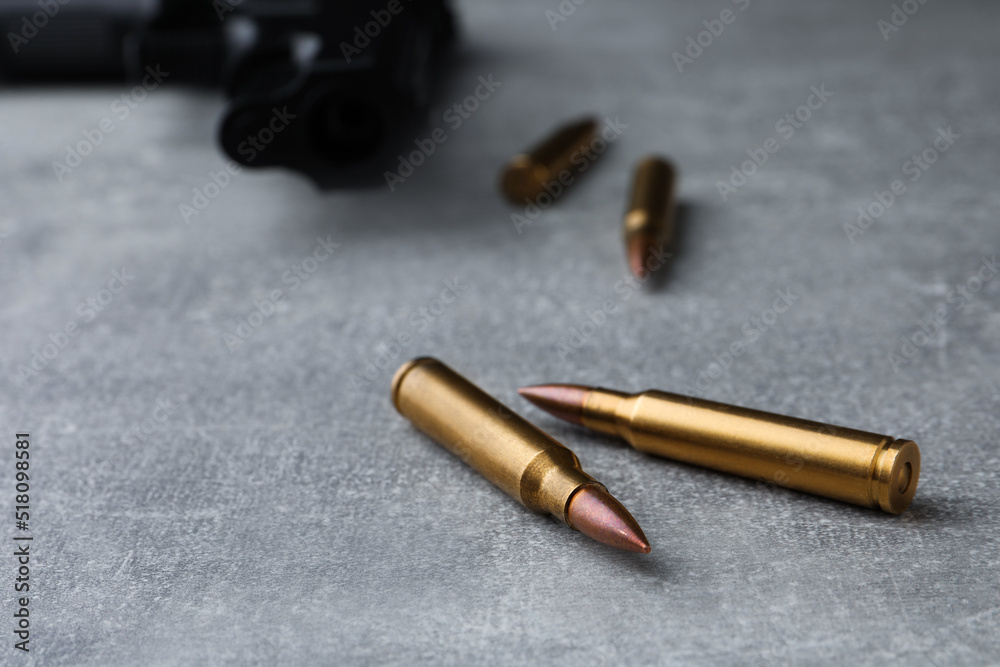 Wall mural Bullets and handgun on light grey table, closeup. Space for text