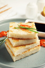 Delicious turnip cake with chili pepper and green onion on plate, closeup