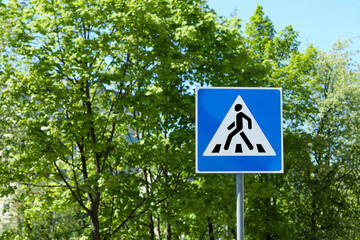 Post with Pedestrian Crossing traffic sign against trees on sunny day