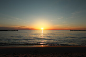 Picturesque view of sandy beach and sea at sunset