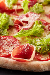 Pizza with prosciutto, lettuce salad and parmesan.