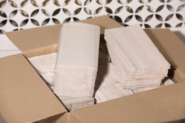 Cardboard box with paper napkins near white wall, closeup