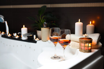 Bathtub with glasses of wine and candles indoors. Romantic atmosphere