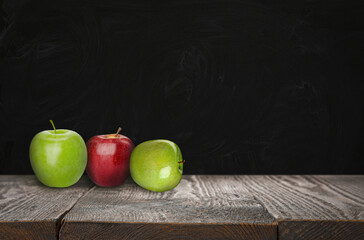 Fresh ripe apples on wooden table near black chalkboard, space for text