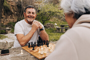 Cheerful senior man playing chess with his wife