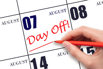 Hand writing text DAY OFF and drawing a line on calendar date 7 August. Vacation planning concept.
