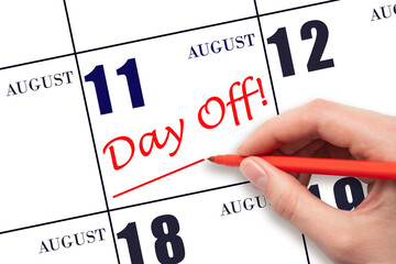 Hand writing text DAY OFF and drawing a line on calendar date 11 August. Vacation planning concept.