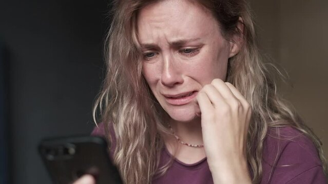 Sad woman looking at the smartphone and crying.
