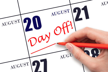 Hand writing text DAY OFF and drawing a line on calendar date 20 August. Vacation planning concept.