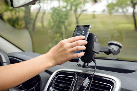 Caucasian hand putting a cellphone on a car phone holder