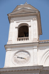 Impressive view of tower of the L'Aquila Cathedral in Rome with blue sky in background.