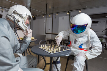 Astronauts playing chess in space suits in capsule hotel