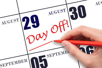 Hand writing text DAY OFF and drawing a line on calendar date 29 August. Vacation planning concept.