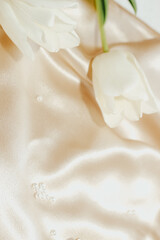 Obraz na płótnie Canvas Bouquet of white tulips on silk golden nude satin background.