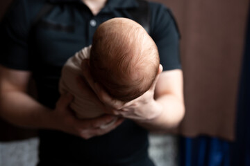 the head of a newborn in the palm of his father. small head of a newborn. child in the arms of a parent