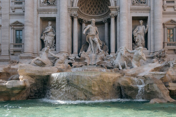 Close-up of one of the most famous landmarks in the world - Trevi Fountain in Rome in bright sunlight with water basin in the foreground.