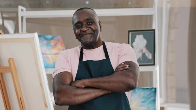 Portrait close up male happy old 50s painter art teacher African American happy elder senior middle-aged man artist talented designer creator posing crossing arms art studio finishing drawing pictures
