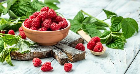 Red raspberries in bowl on white wooden background. Organic Raspberry. Red berry. Long banner format. place for text