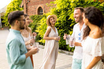 Group of young people cheering and having fun outdoors with drinks