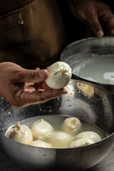 A man working in a small family creamery is processing the final steps of making a cheese. Italian hard cheese silano or caciocavallo, mozzarella