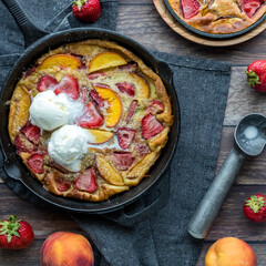 Top down view of a strawberry peach Dutch baby pancake topped with ice cream.