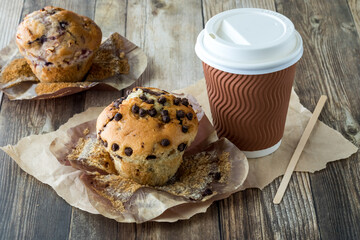 A chocolate chip muffin with the muffin wrapper peeled back, ready for eating.