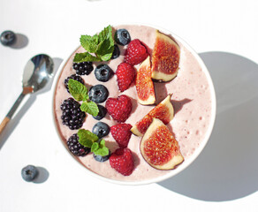 Smoothie bowl with organic ripe berries on the white background. Healthy breakfast concept. Close up