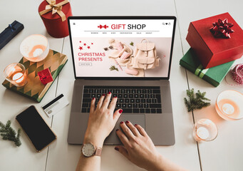 Buying Christmas presents online - internet gift shop - made up content. Woman using laptop...