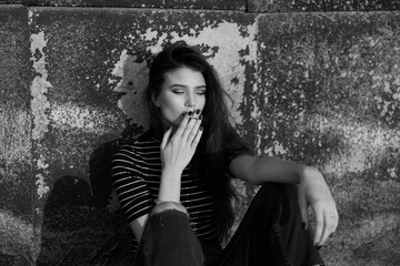 Frontal view of a young girl with trendy look, straight hair, looking at the camera and smoking.