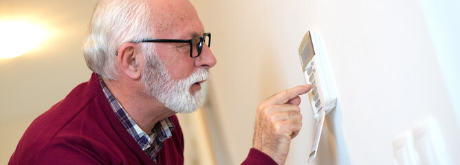 Senior man setting alarm to secure his home from burglary