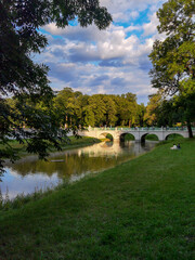 Fototapeta na wymiar Beautiful nature, a city park and a view of the pedestrian restored medieval bridge across the river. Europe, Poland