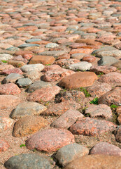 Background with sunlit cobbled street with a sun beam. Textured cobblestone backdrop