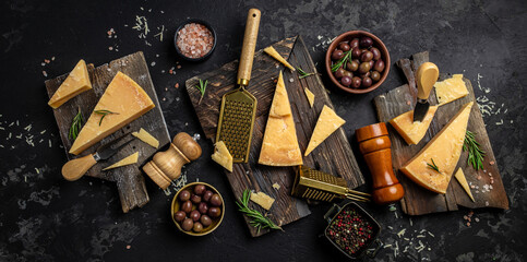 Parmesan cheese on a wooden board, Hard cheese, olives, rosemary and metal grater. place for text, top view