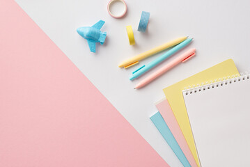 School supplies concept. Top view photo of stationery plane shaped sharpener stack of colorful copybooks pens and adhesive tape on bicolor white and pink background with copyspace