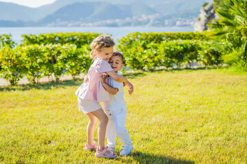 Fototapeta premium Portrait of two cute adorable baby children toddlers hugging and kissing each other, love friendship in childhood concept, best friends forever