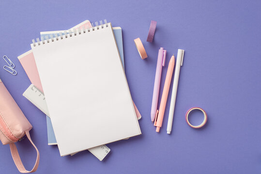 Back to school concept. Top view photo of stack of notebooks pens adhesive tape ruler clips and pink pencil-case on isolated lilac background with blank space