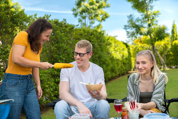 Happy family having barbecue, bbq, party with red wine in outdoor backyard garden of house with happy meal on summer holiday weekend