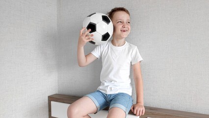 boy holding soccer ball in his hands, boy in a white t-shirt holding soccer ball in his hands on a...