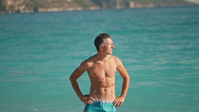 relaxed muscular athletic man on beach against turquoise water of mediterranean sea in Oludeniz Beach in Aegean Sea after swimming. Summer tourist Season Fethiye, Mugla Turkey