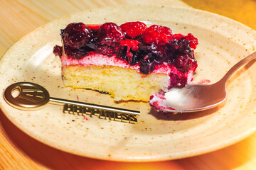 A plate with a bitten piece of sweet berry pie. Golden key with the inscription HAPPINESS. Mood-boosting sweet food. The cure for depression.