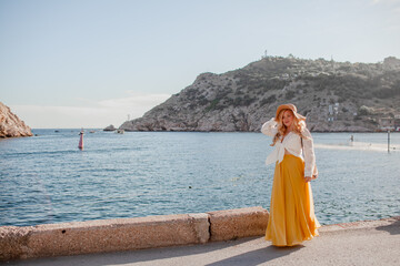 Plus size woman with beautiful blond hair , wearing  boho style clothes, maxy dress,  enjoy the time in nature against blue water of sea