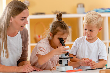 Obraz na płótnie Canvas Young children are looking through the microscope while doing a science preschool project. STEM in education concept.