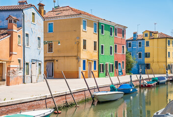 Fototapeta na wymiar View of the canal with moored boats, colorful houses in one of the Italian towns