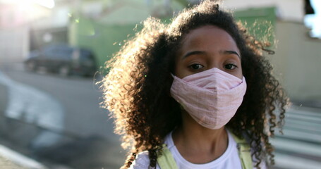 Mixed race girl wearing covid-19 face mask staring at camera