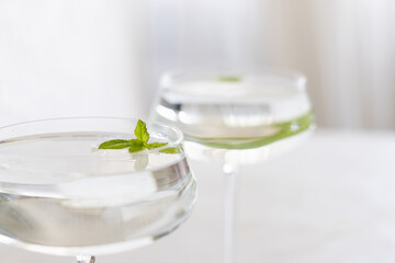 Transparent cocktail with ice cubes in a glass decorated with mint leaves close up